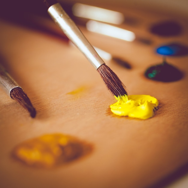Closeup foto em tons de pincel mergulhando em tinta a óleo amarela vívida