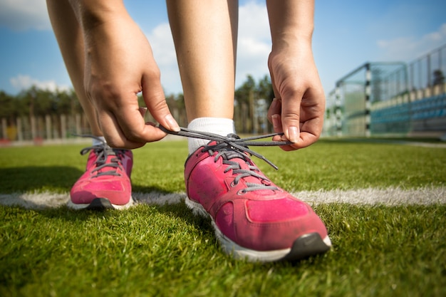 Closeup foto de mujer joven atarse los cordones de los zapatos antes de correr