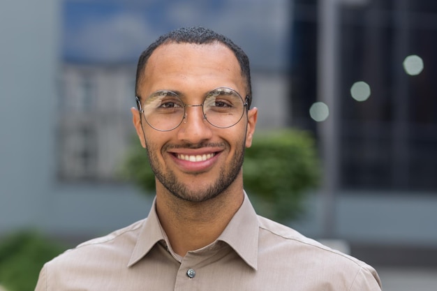 Closeup foto retrato de joven empresario con gafas hombre hispano sonriendo y mirando