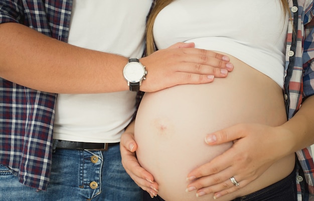 Foto closeup foto tonificada de jovem tocando a barriga da esposa grávida