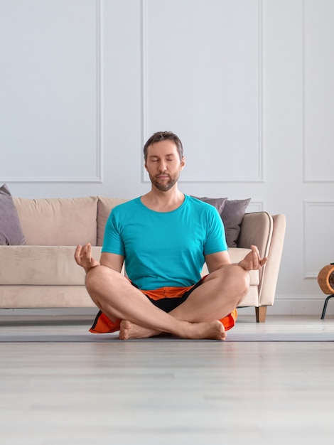 Closeup foto vertical de un hombre de mediana edad meditando en el interior de una casa