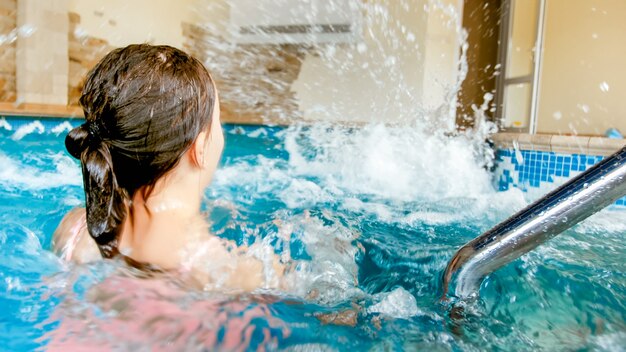 Closeup fotografia de duas adolescentes a brincar e a espirrar água na  piscina