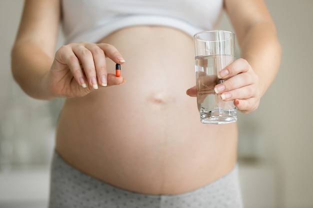 Closeup fotografia de mulher grávida a posar com medicamentos