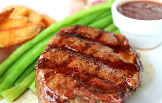 Closeup gegrilltes Filet Mignon Steak mit verschwommenem gedünstetem Gemüse und Bratkartoffeln im Hintergrund