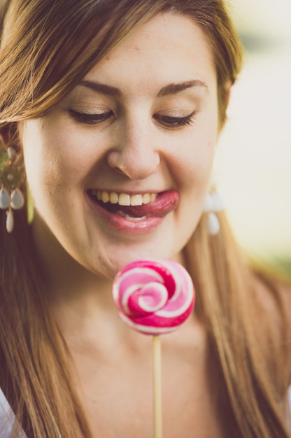 Foto closeup getöntes porträt einer süßen lustigen frau, die ihre lippen am lutscher leckt