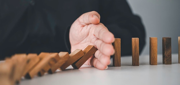 Foto closeup hand a mão de um empresário que está parando ou impedindo um bloco em quedaconceito de proteção contra riscoseliminando o riscox9