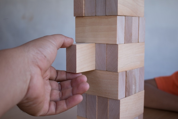 Foto closeup hand spielt spiel der turm aus holzblöcken