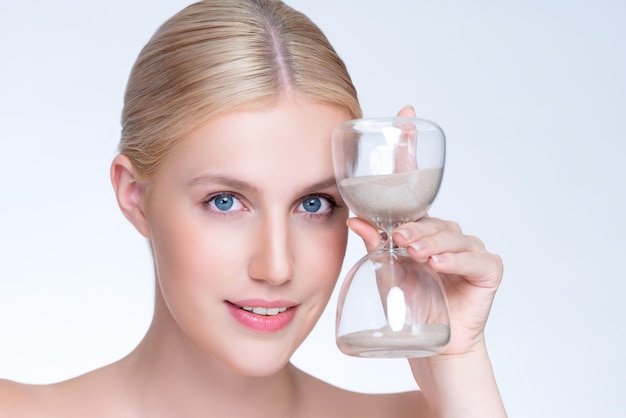 Closeup hermosa mujer agradable con reloj de arena como concepto de cuidado de la piel antienvejecimiento