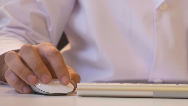 Closeup de un hombre usando la computadora su camisa y corbata en el fondo