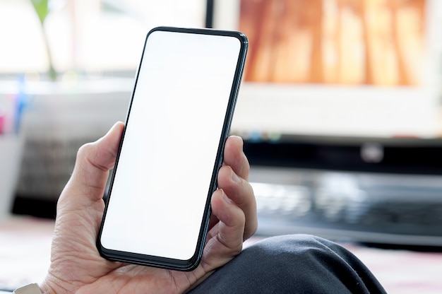 Closeup hombre usando teléfono inteligente con pantalla en blanco mientras está sentado en el escritorio de la oficina, pantalla en blanco para texto