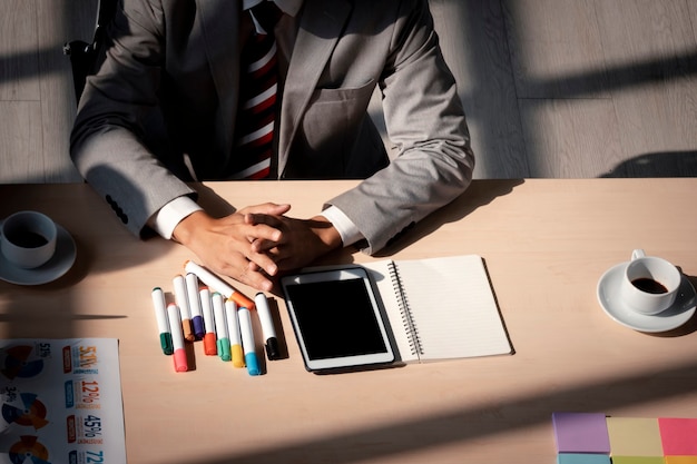 Closeup homem de negócios com roupa formal sentado à mesa com telefone inteligente, papel de documento e café