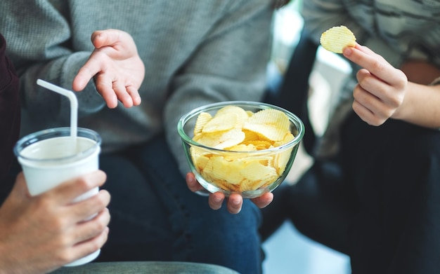 Closeup imagem de amigos bebendo e comendo batatas fritas juntos