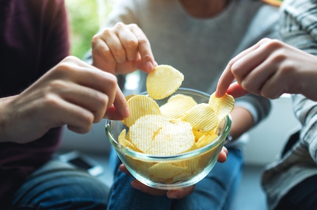 Closeup imagem de amigos compartilhando e comendo batatas fritas na festa em casa juntos