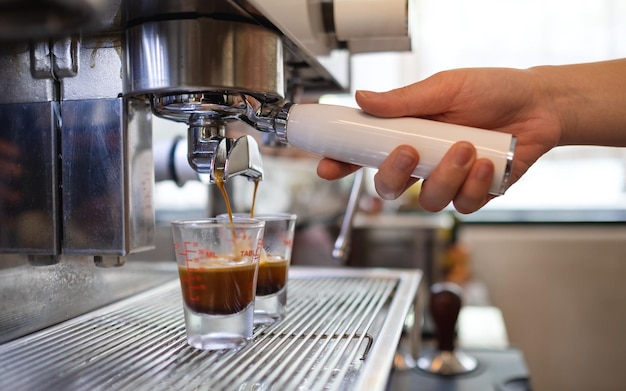 Closeup imagem de barista fazendo café da máquina de café e despejando em copos de shot