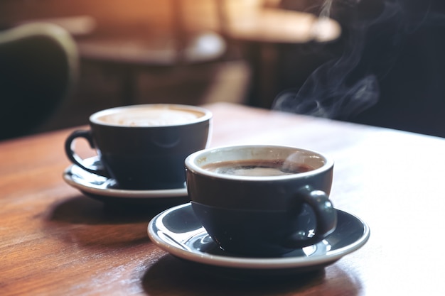 Closeup imagem de duas xícaras azuis de café com leite quente e café Americano na mesa de madeira vintage no café