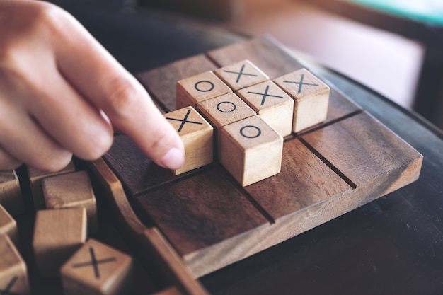 Closeup imagem de pessoas jogando madeira Tic Tac Toe jogo ou jogo de OX