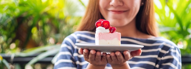 Foto closeup imagem de uma bela jovem asiática segurando um pedaço de bolo de queijo de morango em um pratocloseup imagem de uma bela jovem asiática segurando um pedaço de bolo de queijo de morango em um prato