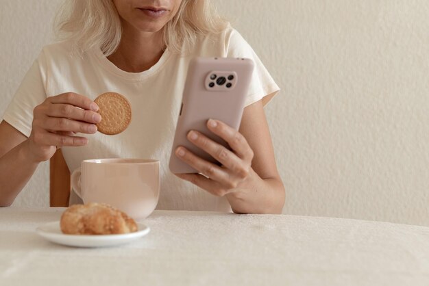 Closeup imagem de uma linda mulher sentada no interior de casa aconchegante e usando as mãos femininas do dispositivo smartphone moderno digitando mensagem de texto via conceito de rede social de celular