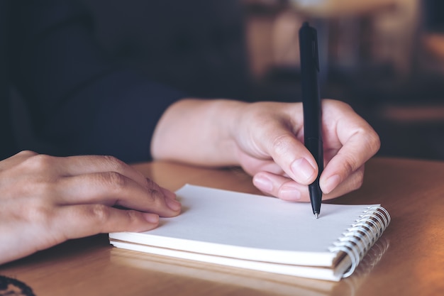 Closeup imagem de uma mão escrevendo em um caderno em branco branco na mesa