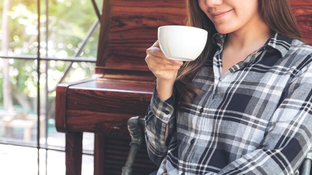 Closeup imagem de uma mulher asiática segurando uma xícara de café antes de beber