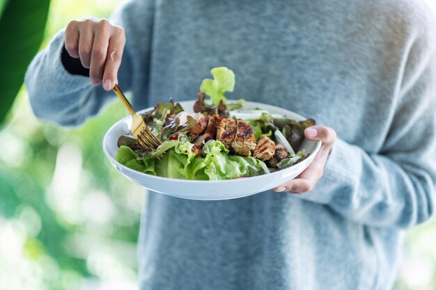 Closeup imagem de uma mulher segurando e comendo salada de frango