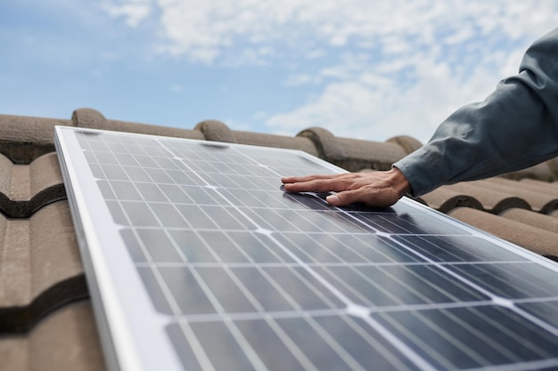 Closeup imagem do empreiteiro de uniforme instalando painel solar no telhado da casa