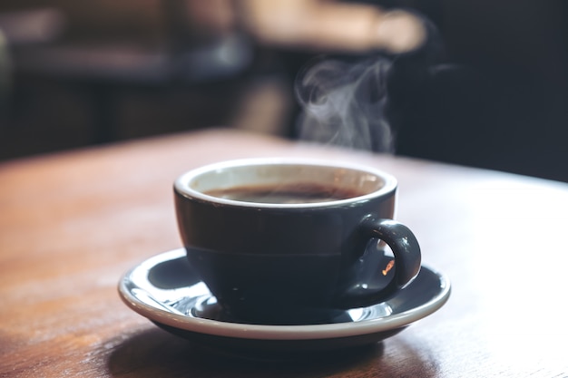 Closeup imagen de una azul tazas de café caliente con humo en la mesa de madera vintage en cafe