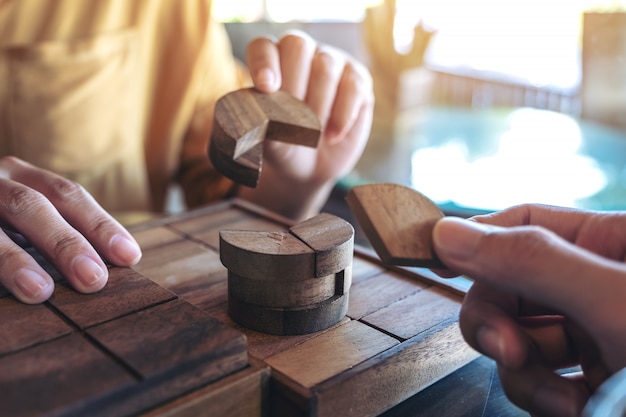 Closeup imagen de dos personas jugando y construyendo un juego de rompecabezas de madera redonda