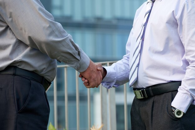 Closeup imagen de gente de negocios en camisas grises y lavanda estrecharme la mano