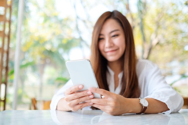 Closeup imagen de una hermosa mujer asiática sosteniendo y usando teléfono móvil