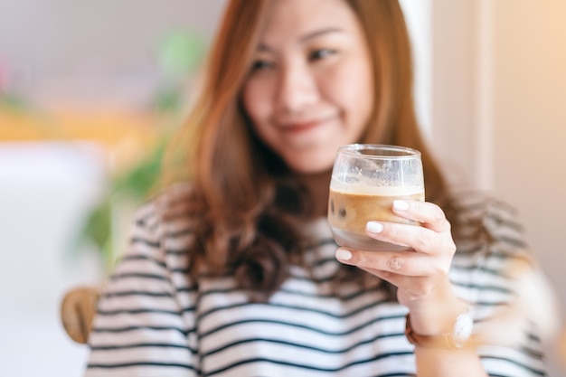 Closeup imagen de una hermosa mujer sosteniendo un vaso de café helado para beber en la cafetería