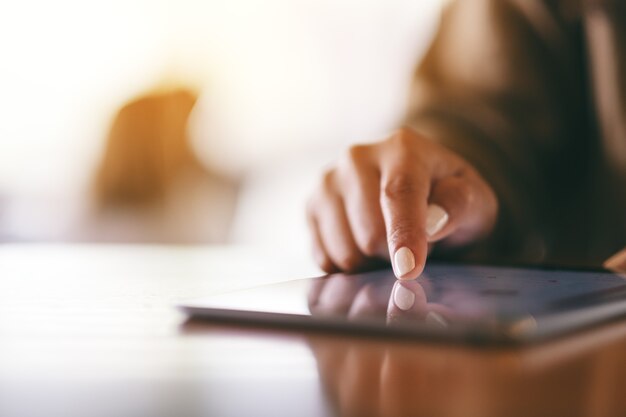 Closeup imagen de una mujer apuntando con el dedo en el tablet pc en la mesa de madera