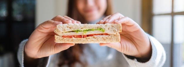 Closeup imagen de una mujer asiática sosteniendo y comiendo sándwich de trigo integral