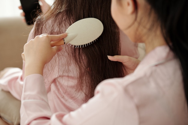 Closeup imagen de mujer cepillando y desenredando el cabello largo de su amiga
