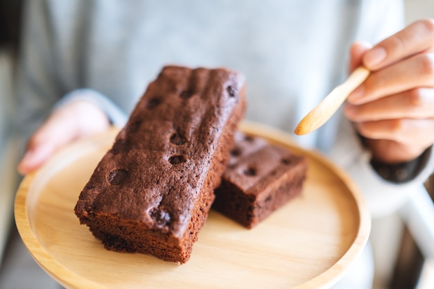 Closeup imagen de una mujer comiendo delicioso pastel de brownie con cuchara