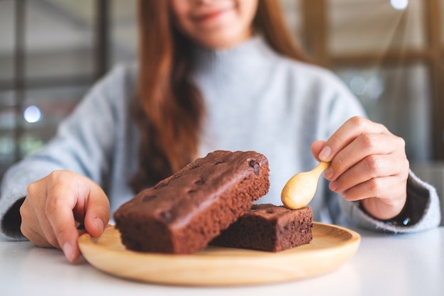 Closeup imagen de una mujer comiendo delicioso pastel de brownie con cuchara