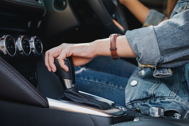 Closeup imagen de una mujer conductora cambiando la palanca de cambios automática mientras conduce un coche