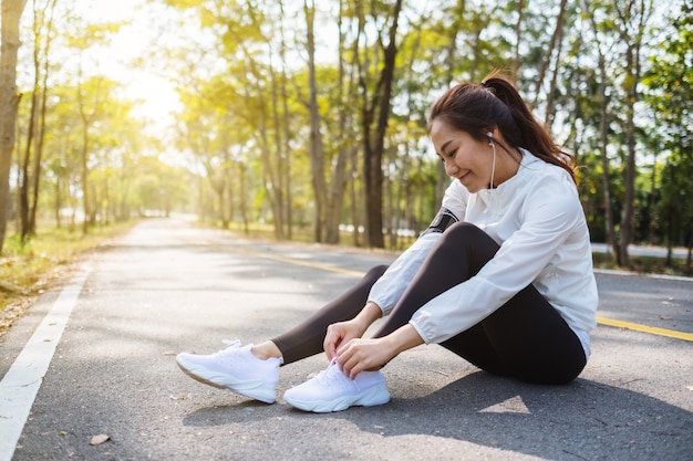 Closeup imagen de una mujer corredor atarse los cordones de los zapatos y preparándose para correr en el parque de la ciudad