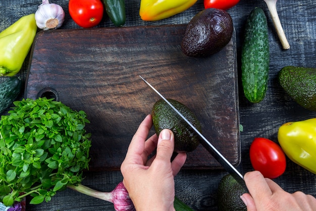 Closeup imagen de una mujer cortando y picando aguacate con un cuchillo sobre la plancha de madera