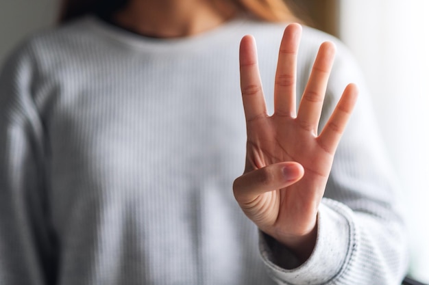 Closeup imagen de una mujer haciendo y mostrando el signo de la mano número cuatro