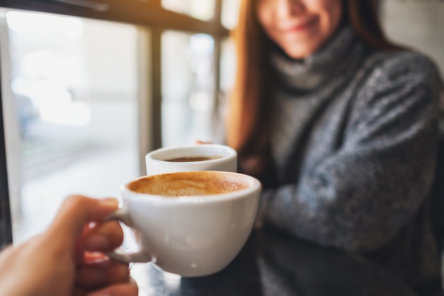 Closeup imagen de una mujer y un hombre tintineo de tazas de café en el café