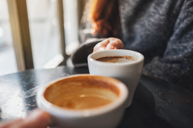 Closeup imagen de una mujer y un hombre tintineo de tazas de café en el café