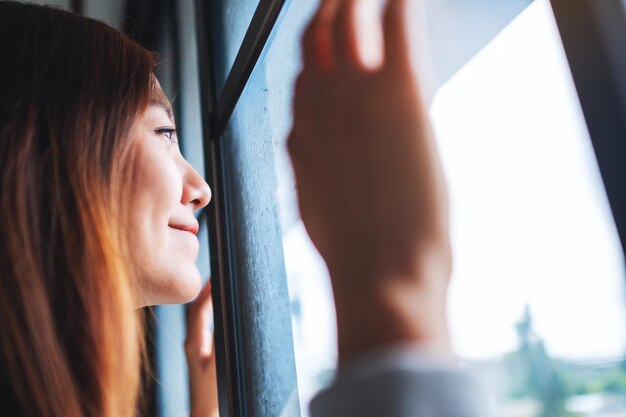 Closeup imagen de una mujer joven tocando la ventana mientras mira afuera