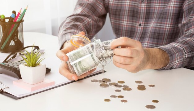 Foto closeup imagen de mujer joven vertiendo monedas de un frasco de vidrio con ahorros de dinero