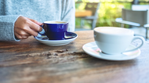 Closeup imagen de una mujer sosteniendo y bebiendo café caliente al aire libre