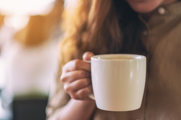 Closeup imagen de una mujer sosteniendo una taza blanca de café caliente