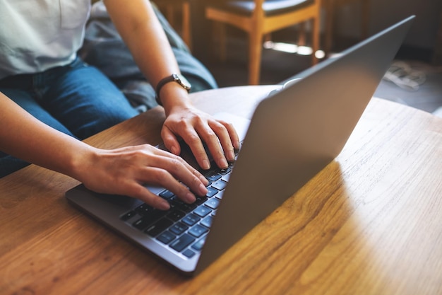 Closeup imagen de una mujer trabajando y escribiendo en el teclado de la computadora portátil sobre la mesa