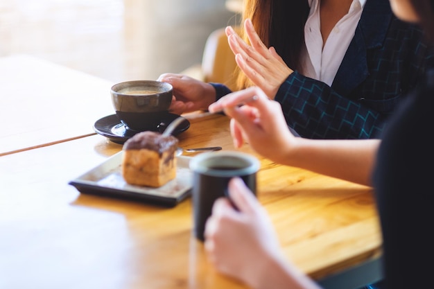 Closeup imagen de mujeres disfrutaron comiendo postre y bebiendo café juntos en la cafetería