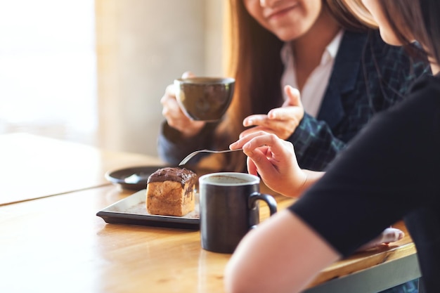 Closeup imagen de mujeres disfrutaron comiendo postre y bebiendo café juntos en la cafetería