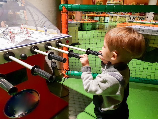 Closeup imagen de niño de 3 años jugando hockey de mesa en el parque de atracciones